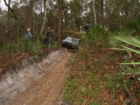 1995 Ford Bronco - A group of people watch as a green SUV navigates a challenging off-road trail.