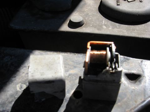 1994 Ford Bronco - Close-up of an automotive relay and its cover, showing internal copper wiring and electrical contacts.
