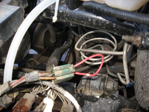 1994 Ford Bronco - Close-up view of the engine bay wiring harness, a red wire connected to a fuse holder.