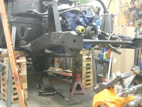 1967 Ford F-250 - Truck frame and engine assembly supported by jack stands and blocks in a workshop environment.