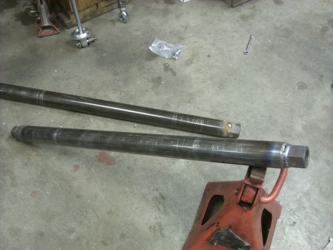 1967 Ford F-250 - Two metal shafts are shown, one supported by a jack stand, in a workshop setting.