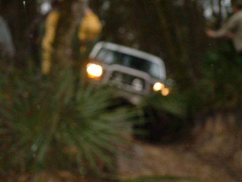 1995 Ford Bronco - This 1995 Ford Bronco navigates a wooded trail with its headlights on.