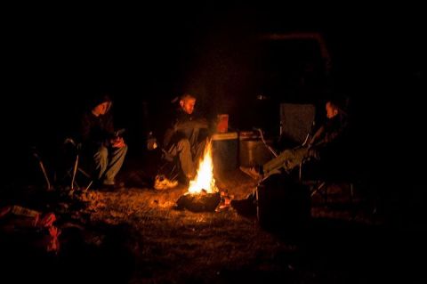 1995 Ford Bronco - Friends gather around a campfire, enjoying the warmth and darkness of the night.