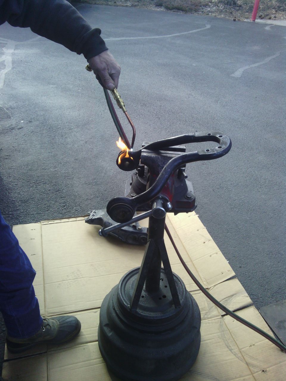 Person heating a car suspension part in a vise with a torch