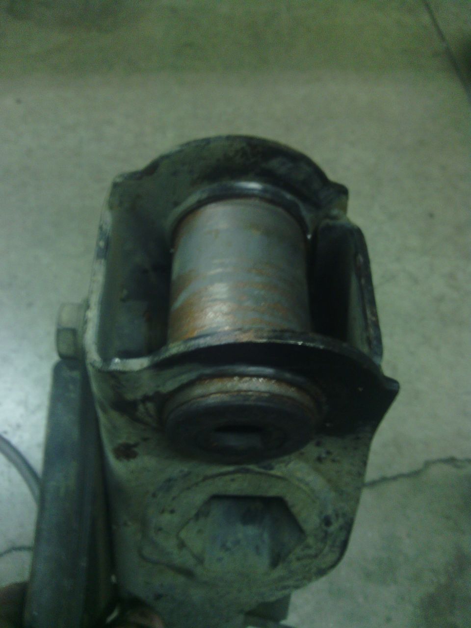 Close-up of a rusty, worn suspension component with a cylindrical bushing