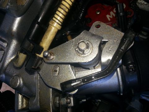1994 Ford Bronco - Close-up view of a throttle body linkage mechanism, showing metal components and a yellow-striped hose.