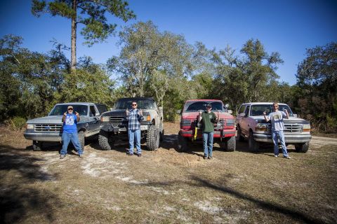 1995 Ford Bronco - Four people pose with their lifted Ford trucks and SUVs in an outdoor setting.