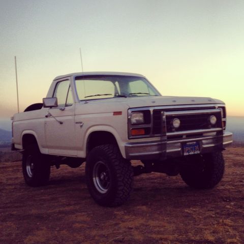 1981 Ford Bronco - This lifted Ford Bronco is parked on a hill overlooking a valley as the sun sets.