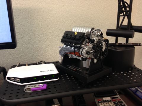 2010 Dodge Challenger - A detailed model engine is displayed on a stand, accompanied by electronic accessories.