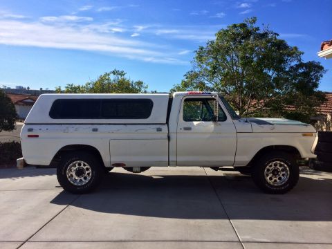 1977 Ford F-350 - This 1977 Ford F-350 pickup is equipped with a white camper shell and aftermarket wheels.