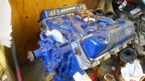 1979 Ford F-150 - A blue Ford V8 engine sits in a workshop, showing the Ford logo on its valve cover.