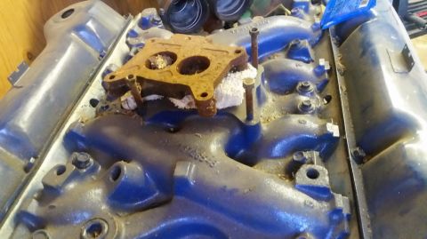 1979 Ford F-150 - This is a close-up view of an engine intake manifold, showing a rusty carburetor spacer.