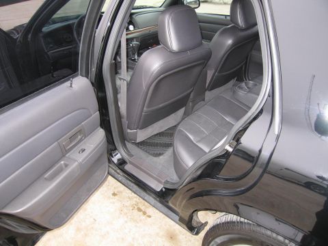 1985 Ford Crown Victoria LTD - The interior of a black Ford Crown Victoria is shown, with a focus on the rear seating area and the driver's side door.
