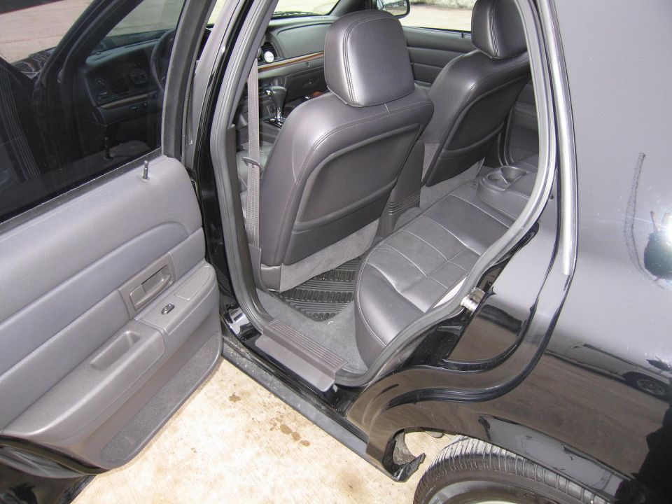 Interior of a black Ford Crown Victoria, showing the back seats and door panel