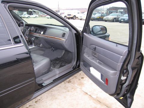 1985 Ford LTD Crown Victoria - The interior of a black Ford Crown Victoria is shown with the passenger door ajar, revealing the dashboard and seating area.
