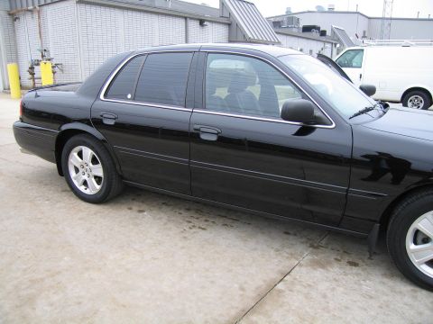 1985 Ford LTD Crown Victoria - Side profile of a black sedan, showing its doors, windows, and wheels.