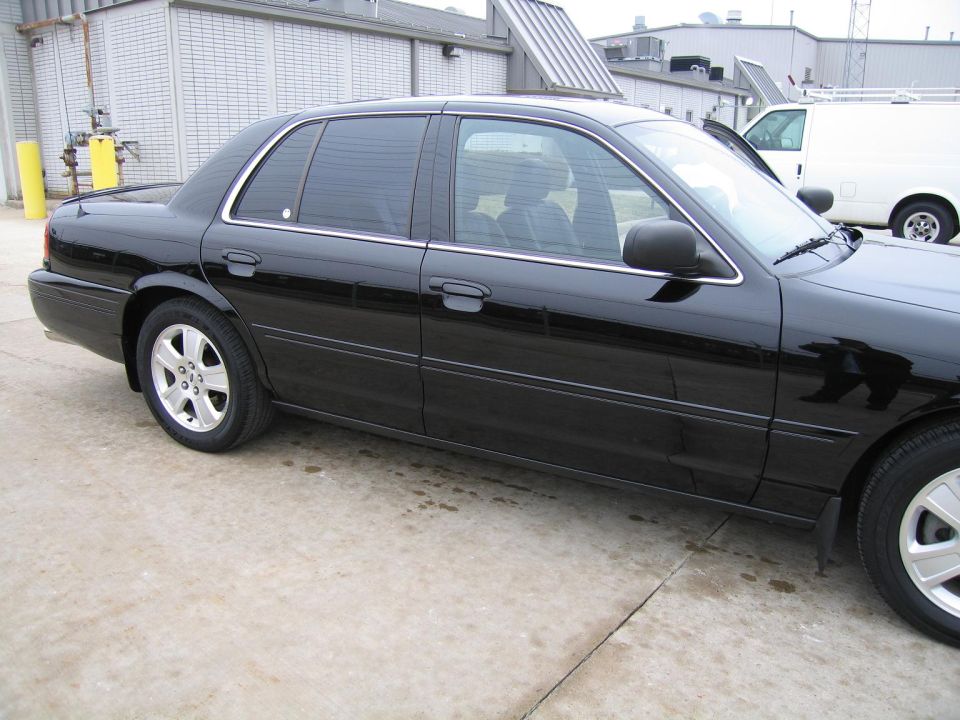 Black sedan parked on concrete, side view