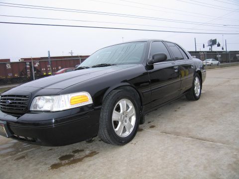 1985 Ford LTD Crown Victoria - Black sedan parked outdoors with train cars and utility poles visible in the background.