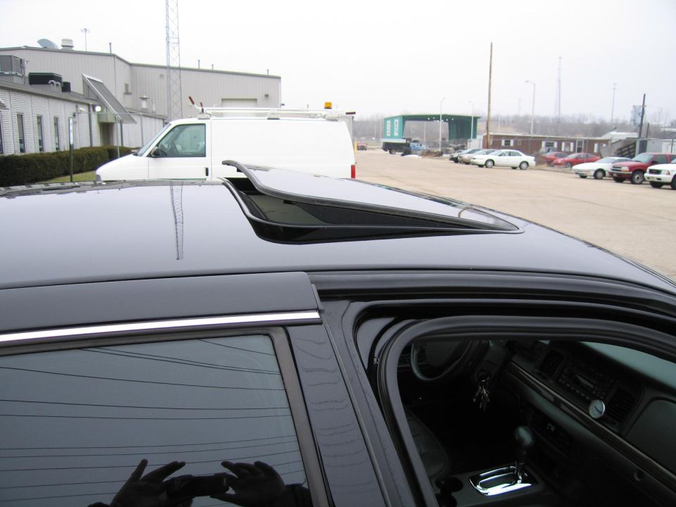 Black car interior with open sunroof, dashboard, and gear shift visible