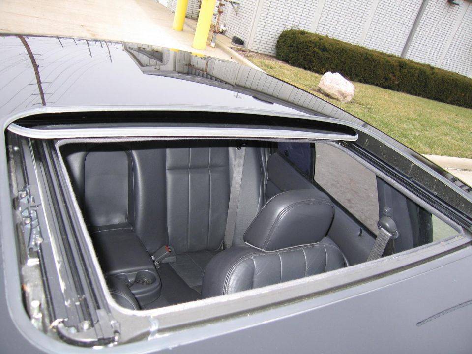 Black leather interior with open sunroof, showing rear seats and cup holders