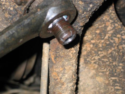 1995 Ford Bronco - Close-up view of a rusted metal rod end with a bolt and blue grease.