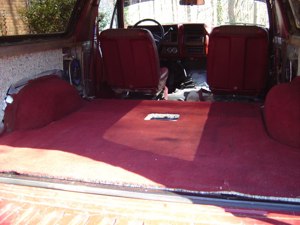 Bronco interior from cargo area, red carpet and front seats, rear seats removed