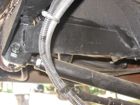1988 Ford Bronco - Close-up of the undercarriage shows various hoses and wiring attached to the vehicle's frame.