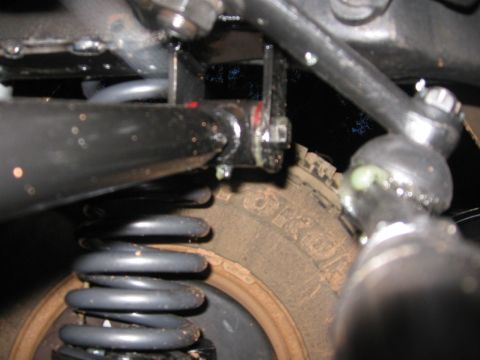 1988 Ford Bronco - Detail shot of vehicle suspension system, including coil spring and steering linkage, with a portion of the tire visible.