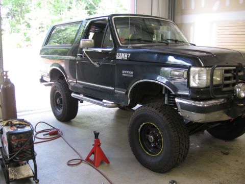 1988 Ford Bronco - A dark blue Ford Bronco is parked in a garage with welding equipment nearby.