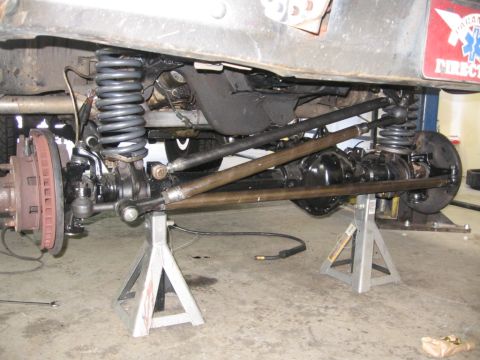 1988 Ford Bronco - The underside of a vehicle is shown, focusing on the front axle and suspension system, which is elevated on jack stands.
