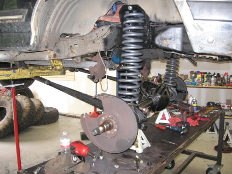 1988 Ford Bronco - Vehicle suspension components, including large coil springs and brake assembly, are visible during a repair or modification.