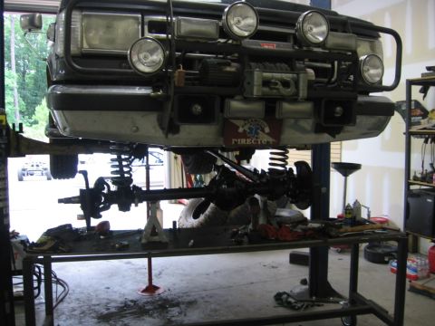 1988 Ford Bronco - 1988 Ford Bronco front end undergoing maintenance on a vehicle lift in a garage.
