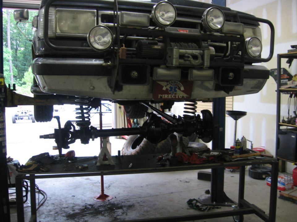 1988 Ford Bronco front end with winch and auxiliary lights, raised on a lift for service