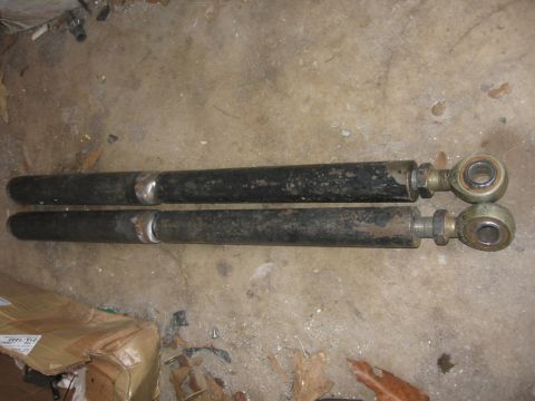 1988 Ford Bronco - Pair of suspension control arms shown on a concrete floor.