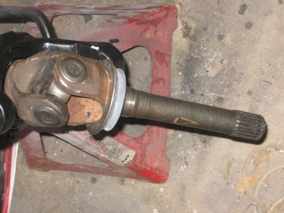 Driveshaft U-joint connected to a splined axle shaft, resting on red jack stands