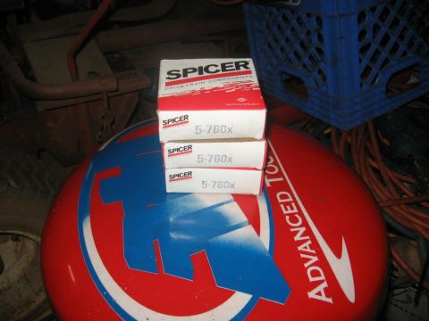 1988 Ford Bronco - Boxes of Spicer drivetrain components are stacked on a stool in a workshop setting.
