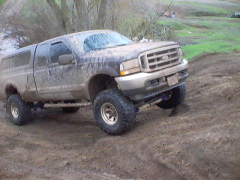 1976 Ford F-100 - This lifted Ford Super Duty pickup truck is covered in mud after driving on a dirt track.