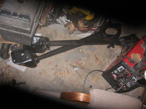 1988 Ford Bronco - Automotive suspension parts and a battery charger are visible on a concrete floor.