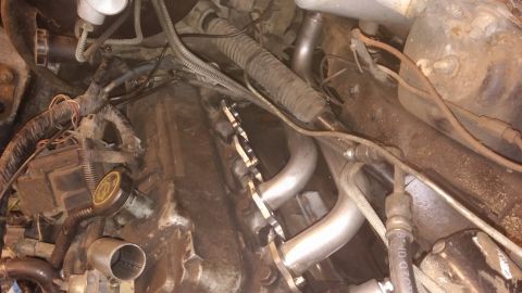 1995 Ford Bronco - Custom exhaust headers installed in an engine bay, with visible wiring and engine components.