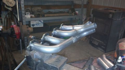 1995 Ford Bronco - Custom exhaust headers are clamped in a vise in a workshop setting, ready for installation.