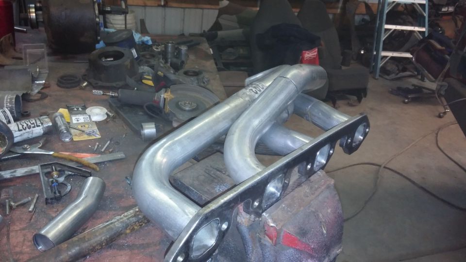 Custom exhaust headers clamped in a vise on a workbench