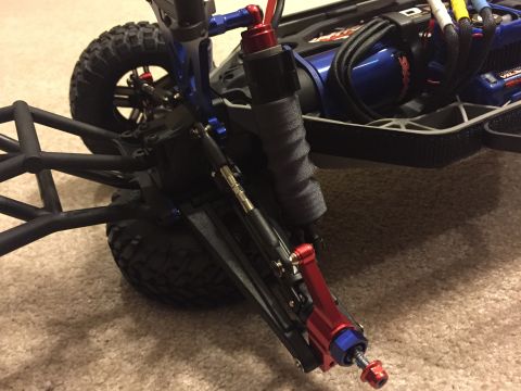 2014 Dodge 1500 - Close-up of an RC car's front suspension assembly, showing custom aluminum upgrades and a roll cage structure.