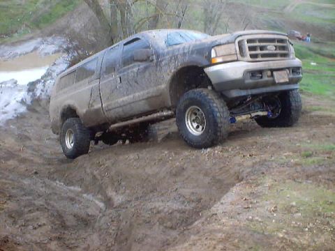 1976 Ford F-100 - This lifted SUV navigates a muddy off-road course, demonstrating its capabilities.