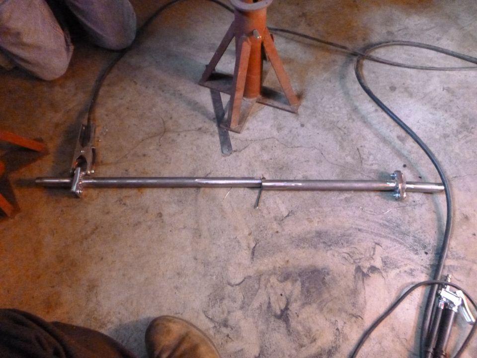 metal rod with flanges on ends, welding equipment nearby