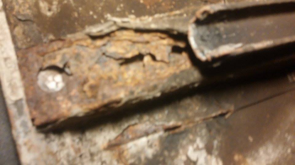 Heavily rusted metal frame section with a bolt head visible