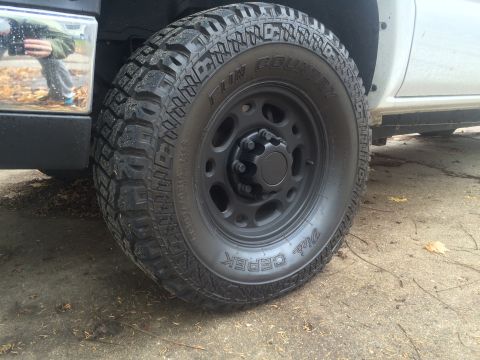 2006 Chevrolet Silverado 2500 - A close-up view of a black wheel and tire on a white truck, with "Fun Country" and "Super Swampers" visible on the tire sidewall.