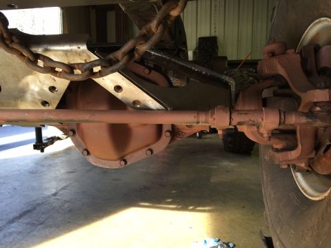 1994 Ford Bronco - This photo shows the underside of a vehicle, focusing on the rear axle and suspension system, with a heavy chain attached.
