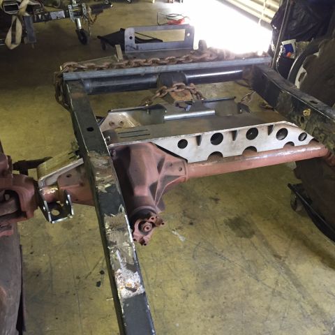 1994 Ford Bronco - Close-up view of a vehicle's frame and axle components, suspended by chains.