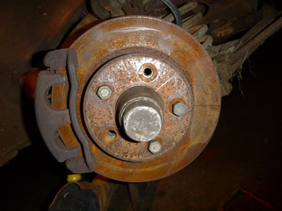 close-up of a rusty car brake rotor and caliper assembly