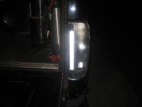 1988 Ford Bronco - A modified tail light assembly is visible on the rear of a vehicle, with a chrome tank and strap inside.